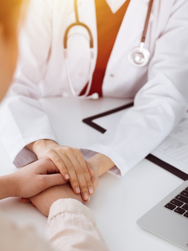 Doctor holding patient's hand during fertility consultation